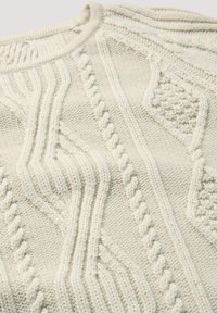 Licht beige gebreide trui met gebogen kabelpatronen en een geribde halslijn. Zachte stof met verschillende steekdetails door het geheel.