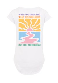 Weißes T-Shirt mit buntem Grafikdesign: Sonne, Wasser und Text. Der Text lautet: "Wenn du die Sonne nicht finden kannst, sei die Sonne."