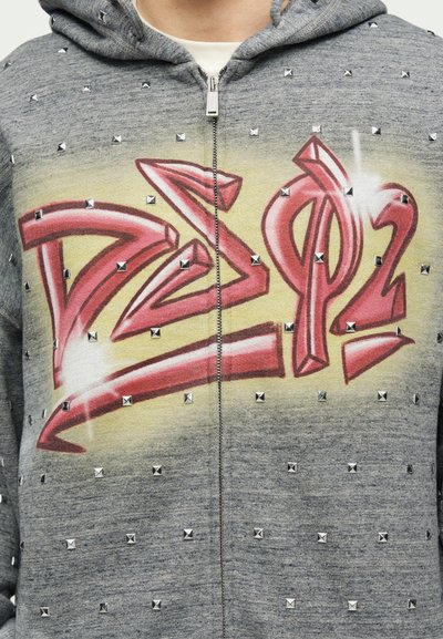 Γκρι φούτερ με φερμουάρ με κόκκινα γράμματα σε στυλ γκράφιτι "DSQ2", κίτρινο φόντο και ομοιόμορφα τοποθετημένα ασημένια καρφιά στο ύφασμα.