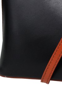 Schwarze Ledertasche mit einem orangefarbenen Ledergriff. Glatte Textur mit sichtbaren Nähten. Kompakte rechteckige Form.