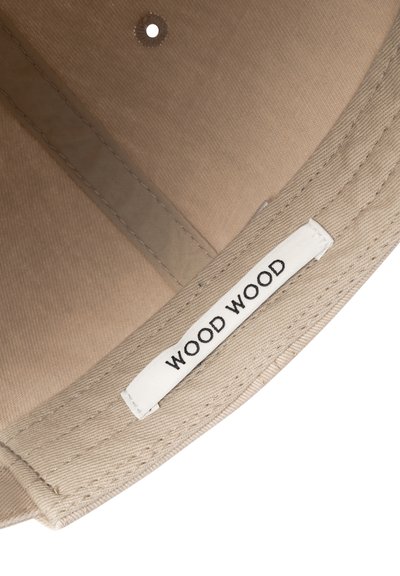 Μπεζ ύφασμα καπέλο τύπου bucket με ορατές ραφές και εσωτερική λευκή ετικέτα με το κείμενο "WOOD WOOD" σε μαύρα κεφαλαία γράμματα.