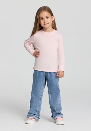 Camicia rosa chiaro a maniche lunghe con scollatura rotonda abbinata a jeans blue denim a vestibilità comoda. L'outfit presenta un design rilassato e uno stile casual.