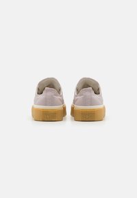 Világos rózsaszín vászon sportcipők, texturált felülettel, gumitalppal és tapadós talppal, az saroknál "CONVERSE ALL STAR" felirattal.
