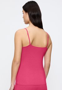 Fuchsia hemdtop met verstelbare dunne schouderbanden, gemaakt van zachte stof, met een getailleerd ontwerp en een naadloze achterkant.