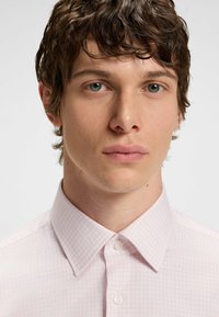Lichtroze geruite overhemd met een pointed collar, knoopsluiting aan de voorkant en een gladde textuur. Bevat kleine witte knopen en een rasterpatroon.