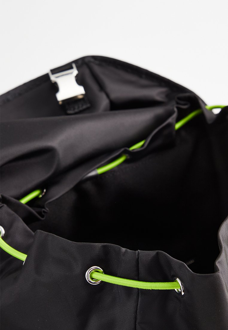 Czarna nylonowa torba z otwartą górą, z zielonym sznurkiem ściągającym i srebrnymi akcentami. Gładka tekstura, minimalistyczny design, przestronne wnętrze.