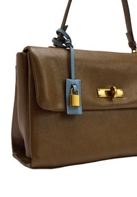 Brązowa skórzana torebka o sztywnym kształcie, z zapięciem na złoty zamek i niebieską skórzaną metką. Gładka faktura z minimalnym zdobieniem.