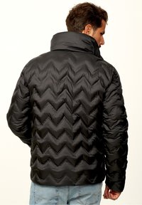 Black puffer jacket featuring a chevron quilted pattern, high collar, and elastic cuffs. Textured surface with a smooth finish.
