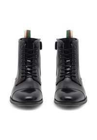 Czarne skórzane botki za kostkę o błyszczącym wykończeniu, okrągłym nosku, prostych sznurówkach oraz tylnym uchwycie z zielonymi i brązowymi paskami.