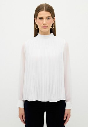 Blusa bianca con collo alto, maniche lunghe in tessuto trasparente e pieghe verticali. L'orlo è curvo, con polsini bottonati e una texture liscia.