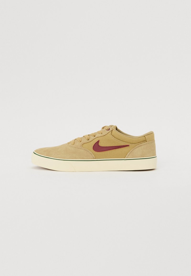 Tan-farbene Wildleder-Sneaker mit einem kastanienbraunen Swoosh, cremefarbener Gummisohle und grünen Akzenten am Rand. Niedrig geschnittenes Design mit Schnürverschluss.