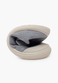 Chaussure slip-on en tissu gris avec une forme arrondie, une semelle beige lisse et un motif en caoutchouc texturé au bas pour l'adhérence.