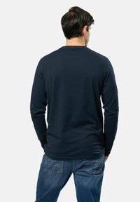 T-shirt à manches longues bleu marine en coton doux, avec un col ras du cou et une coupe décontractée, associé à un jean en denim bleu.