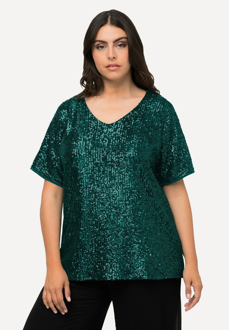 Top in paillettes turchesi con scollatura a V, maniche corte e vestibilità ampia. Presenta una texture scintillante e un orlo dritto. Abbinato a pantaloni neri.
