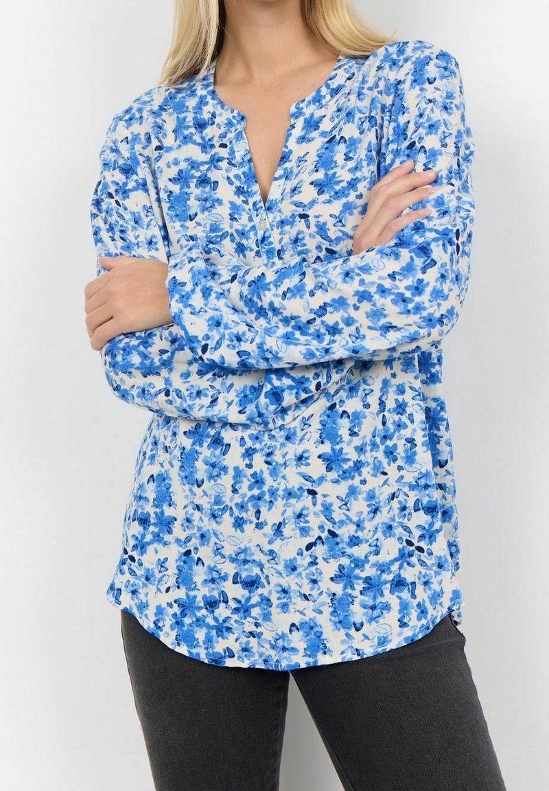 Kwiatowa bluzka z lekkiego materiału, z niebieskim wzorem kwiatowym na białym tle, z dekoltem w kształcie litery V i długimi rękawami.
