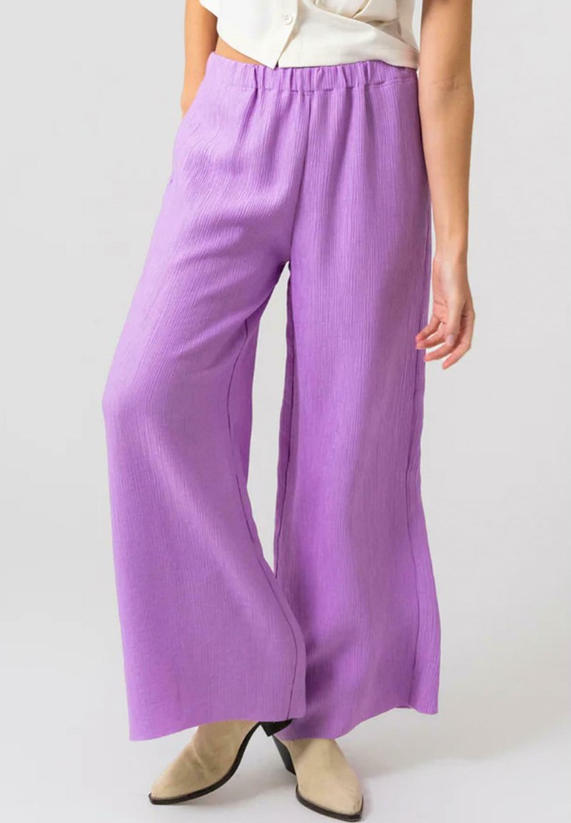Paarse wijde broek van textuurstof, met een elastische tailleband en zijzakken, gecombineerd met beige puntige schoenen.