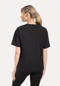 Zwart T-shirt met korte mouwen, gemaakt van glad katoenen stof, voorzien van een ronde hals en een losse pasvorm, gezien vanaf de achterkant.