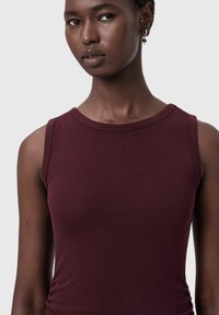 Viininpunainen hihaton paita joustavasta puuvillasta. Mukana pyöreä pääntie ja vartalonmyötäinen leikkaus, hienovaraisella tekstuurilla ja sivurypytyksellä.