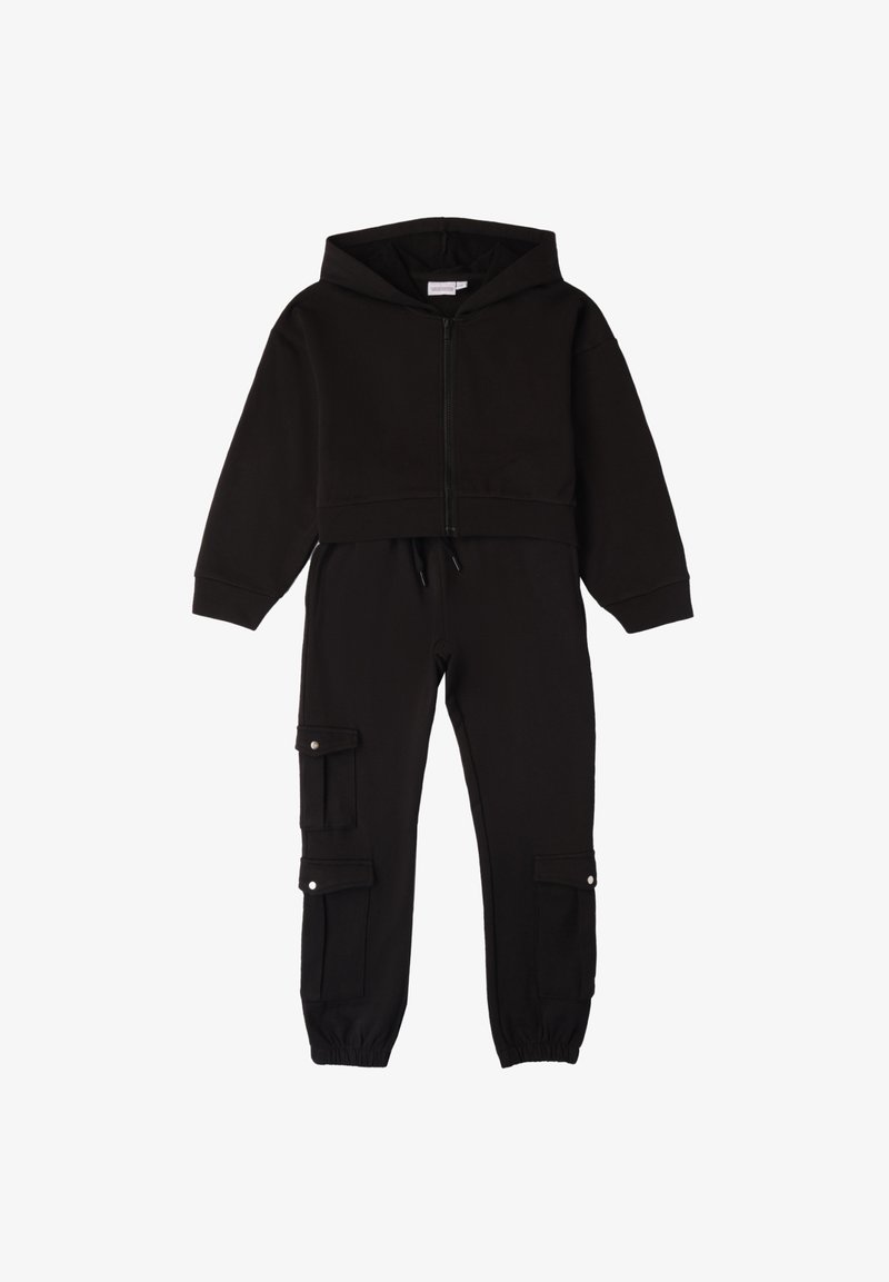 Zwarte cropped hoodie met een voorkant rits en trekkoord; gecombineerd met tapered broek met cargozakken en elastische boorden.