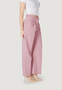 Pantaloni a gamba larga rosa chiaro con una parte anteriore plissettata e una texture liscia, dotati di chiusura con bottone e tasche laterali.