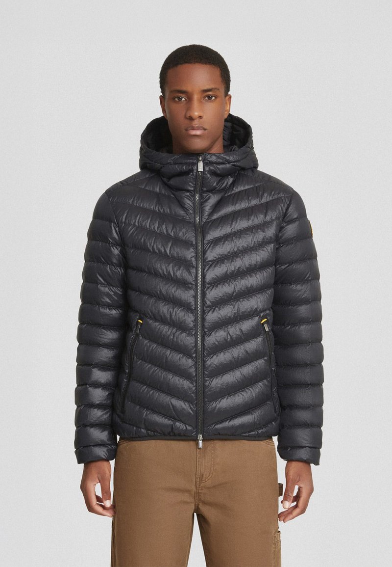 Giacca a vento nera imbottita con motivo a rombi diagonali, cappuccio e tasche con zip. Presenta una finitura lucida e una silhouette slanciata.
