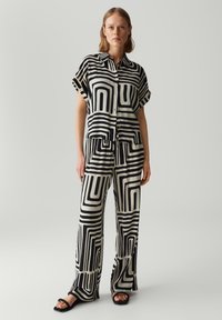Zwart-wit gestreept bijpassend shirt en broek set met korte mouwen, knopen en een losse pasvorm, met geometrische lijnontwerpen.