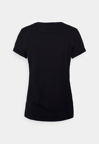 Lyhythihainen musta istuva t-paita esitetty takaapäin yksinkertaista vaaleaa taustaa vasten.