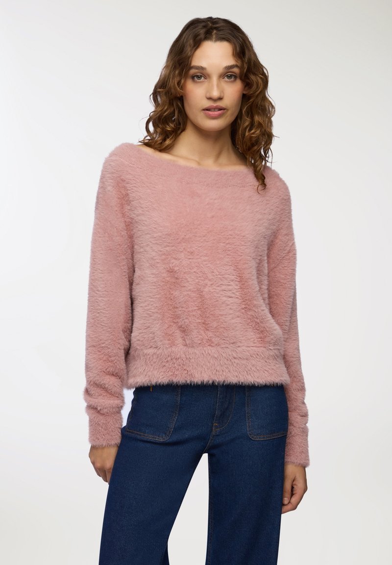Maglione rosa peloso con scollatura ampia, maniche lunghe e orlo corto. Abbinato a jeans in denim scuro, con un fit morbido.