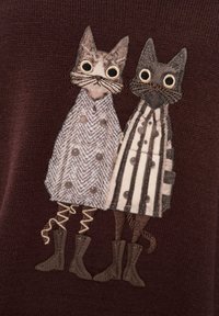 Dzianinowy sweter z dwoma haftowanymi kotami. Jeden ma na sobie płaszcz w jodełkę, drugi w paski, obaj z ozdobnymi butami. Ciemne tło.