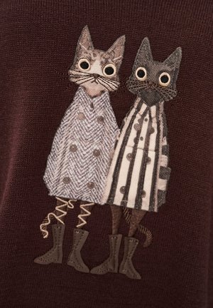 Dzianinowy sweter z dwoma haftowanymi kotami. Jeden ma na sobie płaszcz w jodełkę, drugi w paski, obaj z ozdobnymi butami. Ciemne tło.