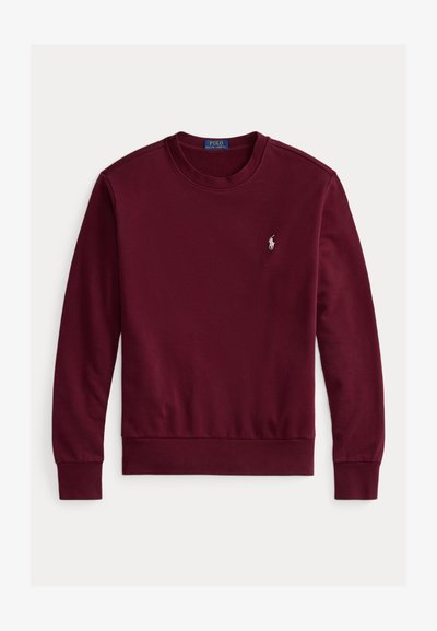 Burgundy színű pulóver, kerek nyakkivágással, hosszú ujjakkal, bordás mandzsettákkal és aljjal, bal oldalon egy kis hímzett logóval. Puha anyagból készült.