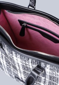 Borsa tote con un'esterno intrecciato in bianco e nero texture. L'interno presenta una fodera a motivi rosa e una tasca con zip per ulteriore spazio di stoccaggio.
