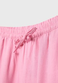 Ceinture de pantalon en tissu rose avec élastique et détail de nœud noué avec un cordon.