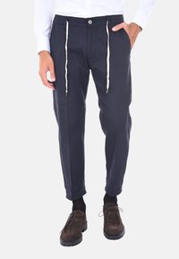Pantaloni navy realizzati in misto cotone, con una vestibilità rilassata, vita con cordino e dettagli color crema, e polsini affusolati.