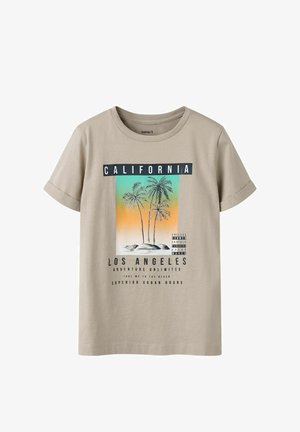 Camiseta beige de manga corta con gráfica de palmeras, fondo degradado de atardecer y texto "California", "Los Ángeles" y frases relacionadas con la playa.