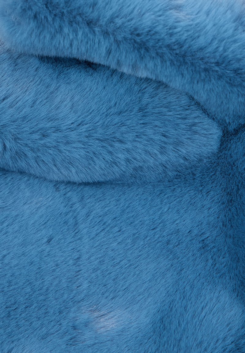 Pelliccia sintetica blu con una consistenza morbida e pelosa. Il materiale appare denso con una superficie liscia e sottili variazioni di tonalità.
