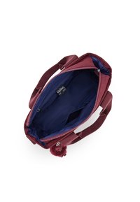 Borsa in tessuto bordeaux con duplice manico corto, chiusura zip e interno blu navy. Presenta un pompon decorativo sulla cerniera.