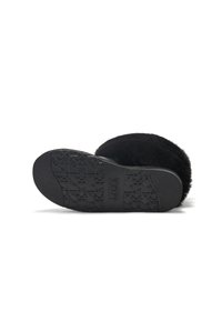 Black slipper with a fluffy upper and textured rubber sole. Notable branding on the sole and soft, plush material. Round shape.