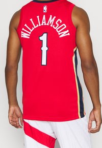 Red basketball jersey featuring "WILLIAMSON" and number "1" in white, with navy and gold side accents. Lightweight, sleeveless design.
