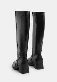 Svarta knähöga stövlar i slätt läder med en definierad skaft, klumpig klack och sidogets för enkel användning.