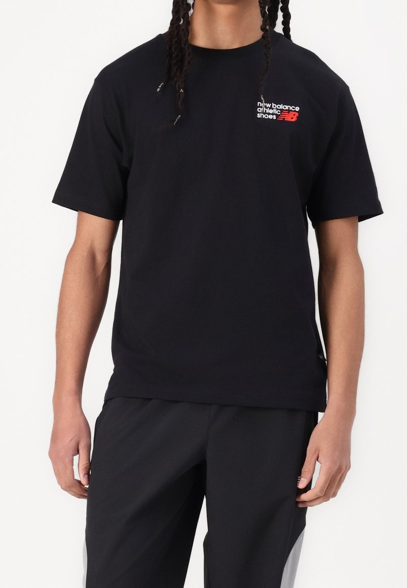 Czarny bawełniany t-shirt z krótkimi rękawami, z małym białym i czerwonym logo na piersi. Dopasowany krój, okrągły dekolt i detal z rozcięciem po bokach.