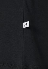Sort bomulds t-shirt med et lille hvidt mærke med et kænguru-logo og teksten "KANGOL" på den nederste søm. Glat tekstur, minimalistisk design.
