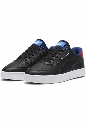 Sneaker in pelle nera con suola bianca, accenti blu e rossi, punta perforata e logo prominente sulla linguetta e sul lato.
