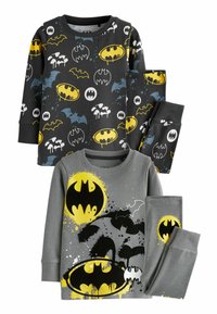 Två uppsättningar barnpyjamaser med Batman-motiv. Den övre uppsättningen har en svart topp med flerfärgade Batman-logotyper; byxorna är svarta. Den nedre uppsättningen har en grå topp som visar en stor gul Batman-logotyp med stänkdetaljer, ihopparad med grå byxor. Båda uppsättningarna är gjorda av mjukt tyg.