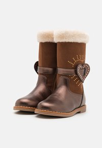 Bottes en suédine marron et en faux cuir métallique brillant, avec un revers en fausse fourrure crème duveteux, des embellissements en forme de cœur et des détails en or.