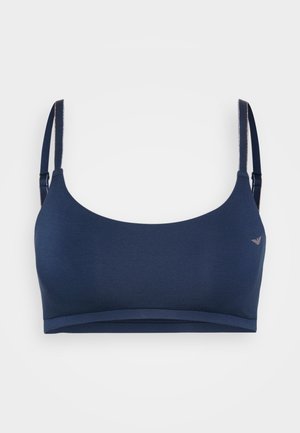 Navy blue sports bra with adjustable straps, a rounded neckline, smooth fabric texture, and a minimalist design featuring a small logo accent.