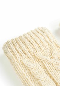 Guanti lavorati a maglia di colore crema con un design a coste e motivi a treccia in rilievo, che mostrano un tessuto testurizzato con filamenti metallici sottili.