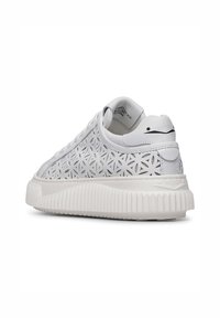 Sneaker bianco con un intricato design a intaglio floreale, dettagli in pelle liscia e una suola in gomma testurizzata e rigata.