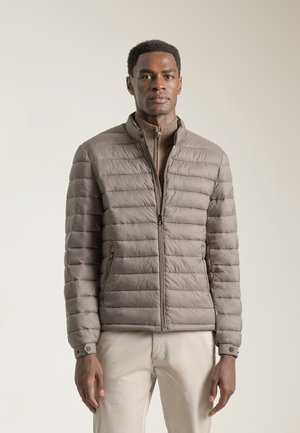 Chaqueta ligera acolchada en taupe con cierre delantero, cuello alto y bolsillos laterales. Tejido suave con un ligero brillo.