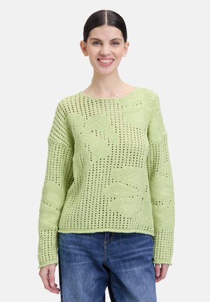 Pull en maille vert clair avec une coupe ample, présentant des motifs en tissages ouverts et des manches longues. Le tissu texturé ajoute de la profondeur au design.